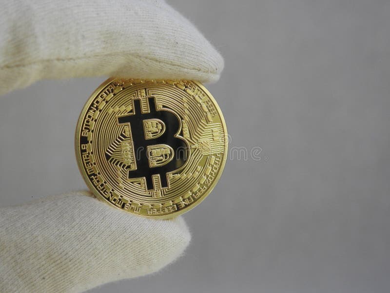 Golden Bitcoin handled with gloves. royalty free stock photo