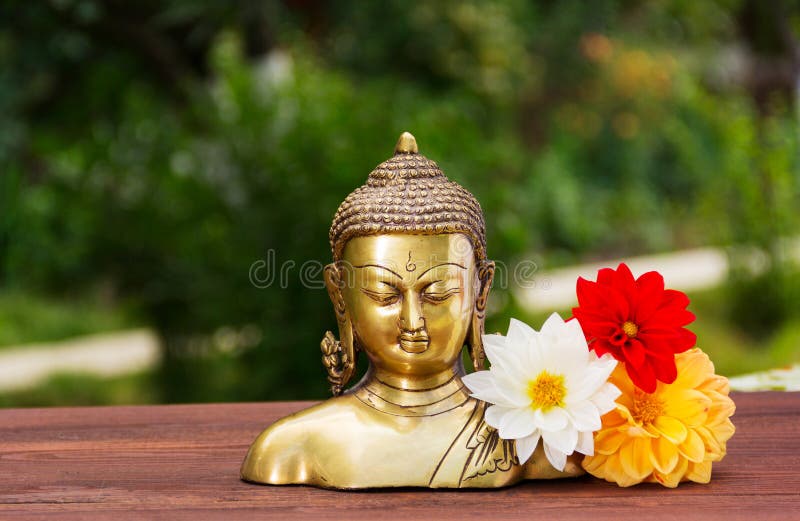 A golden Buddha statue in a summer sunny garden. Buddha and flowers aster. Relax and meditation. Copy space