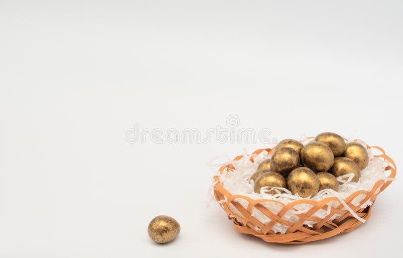 Golden chocolate Easter eggs in egg basket with white paper like a nest. Happy Easter holiday concept. Banner stock images