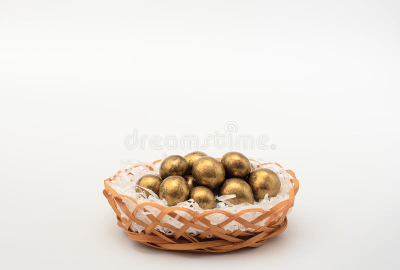 Golden chocolate Easter eggs in egg basket with white paper like a nest. Happy Easter holiday concept. Banner royalty free stock photography