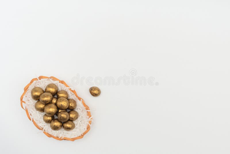 Golden chocolate Easter eggs in egg basket with white paper like a nest. Happy Easter holiday concept. Flat lay style with copy royalty free stock photo