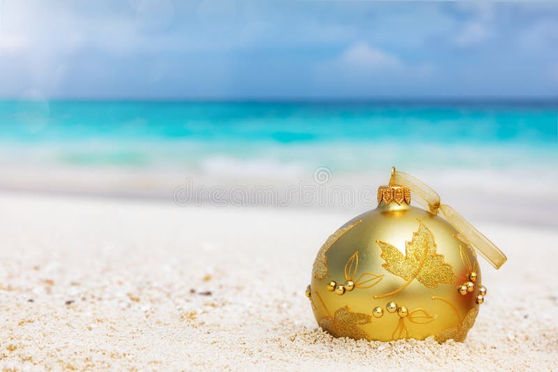 Golden christmas tree ball on a tropical beach