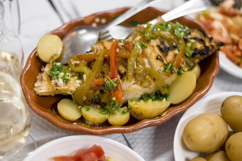 Golden fish with red and green pepper served with cooked potatoes and tomato salad