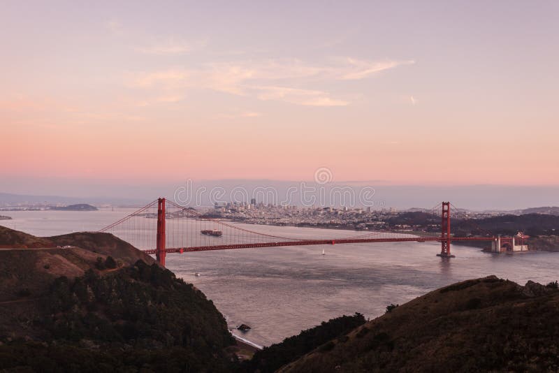 Golden Gate Bridge in pink glow of twilight mountains, skyline