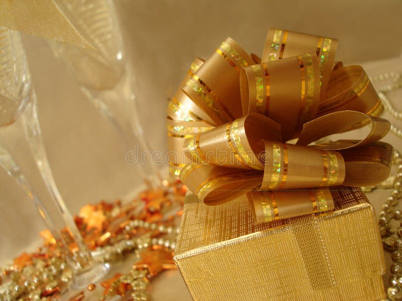 Golden gift box on a beautiful background with champagne glasses