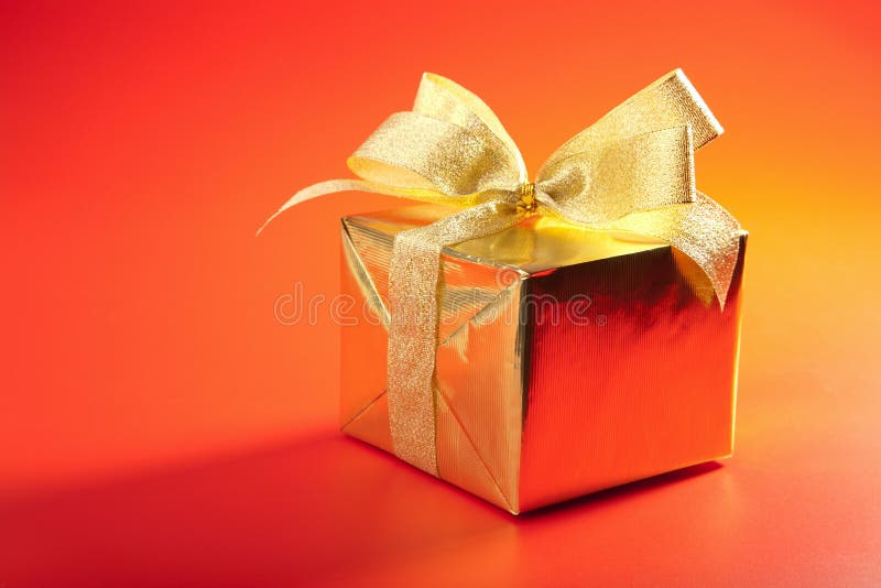 Golden gift box with bow over red stock photo