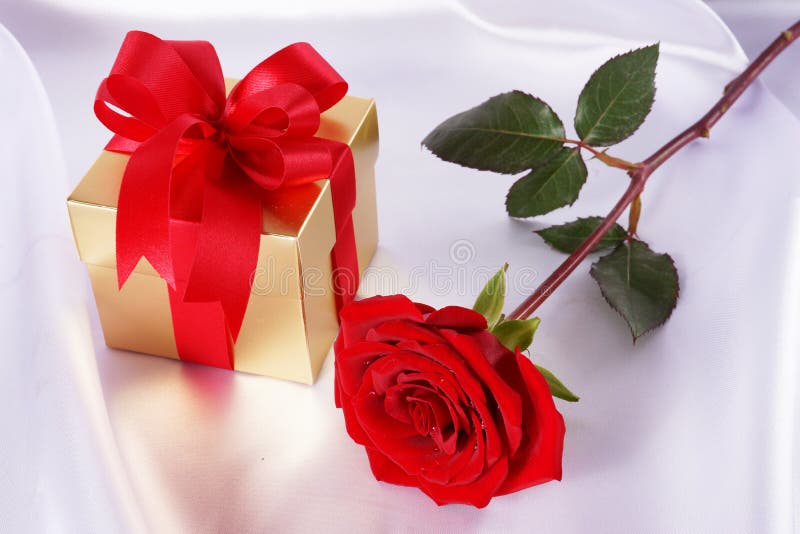 Golden Gift Box and Red Roses on White Satin Background Stock Photo