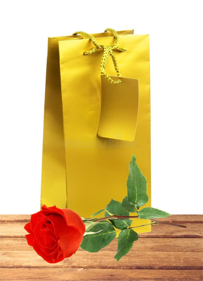 Golden gift shopping bag and red rose isolated on white. Background stock photo Golden gift shopping bag and red rose isolated on white. Background stock photo