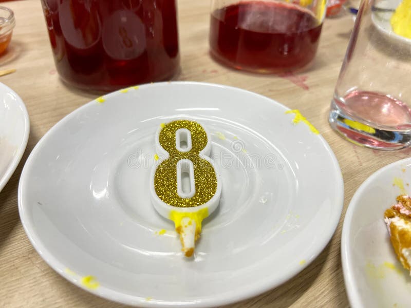 Golden glitter number eight candle resting on white plate celebrating eighth birthday stock images