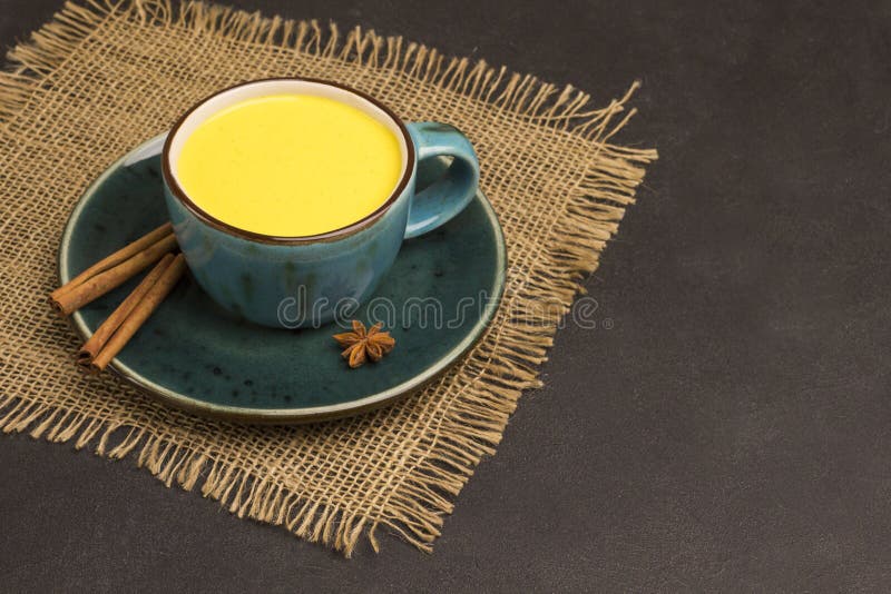 Golden latte on black background with ingredients for cooking. Indian drink turmeric golden milk