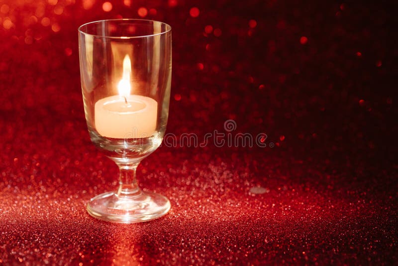 Golden light of candles burning in wine glass with light effect