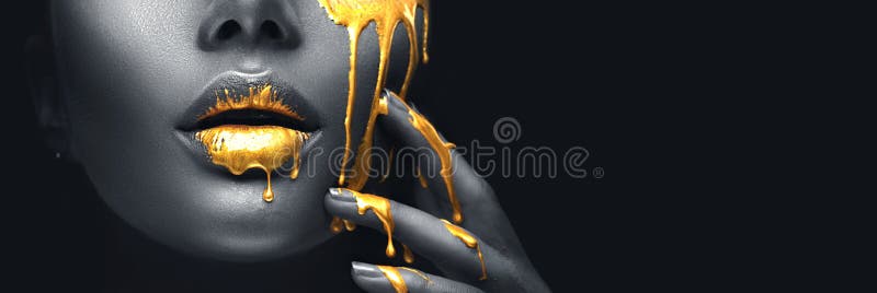 Golden paint smudges drips from the face lips and hand, golden liquid drops on beautiful model girl`s mouth, creative makeup