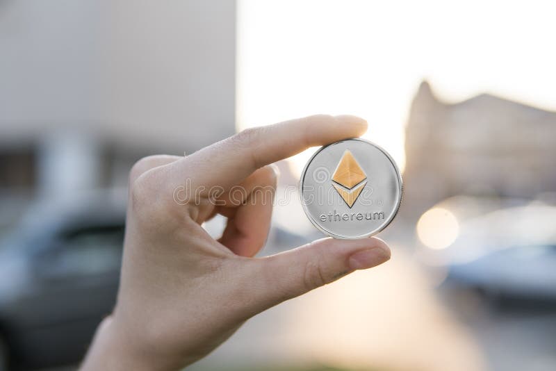 Golden silver Ethereum coin in hand on a blurred sunset background. Hand holding a crypto currency virtual money royalty free stock photos Golden silver Ethereum coin in hand on a blurred sunset background. Hand holding a crypto currency virtual money royalty free stock photos