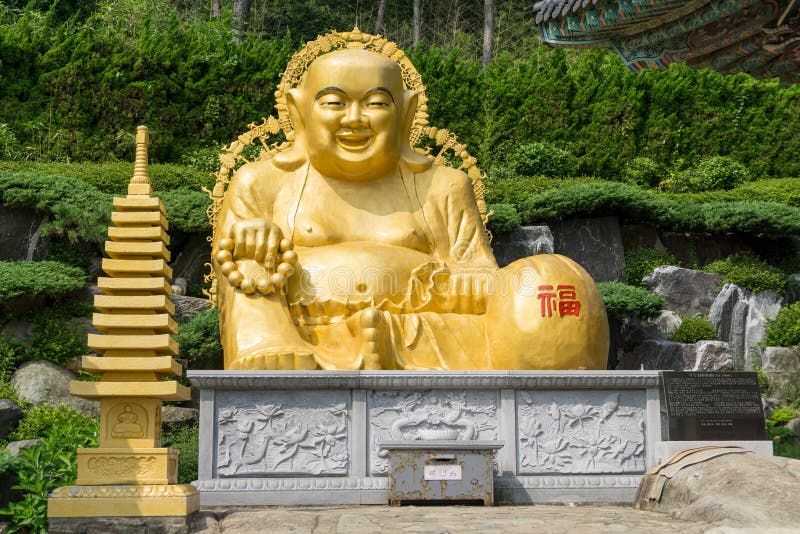 Golden smiling fat Buddha image in sitting position statue at Haedong Yonggungsa Temple in Busan