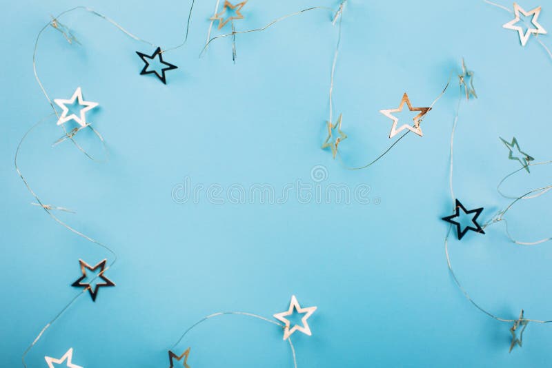 Golden star shaped garland on pastel blue background.