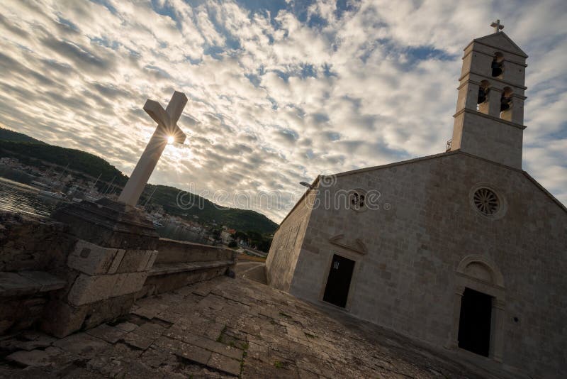 The golden sun rising through dramatic clouds with an old church and cross in the foreground royalty free stock photo The golden sun rising through dramatic clouds with an old church and cross in the foreground royalty free stock photo