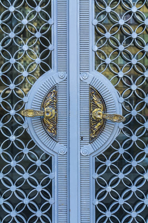 Golden vintage door handles on glass and blue metal decorative doors in Bulgarian castle royalty free stock photography Golden vintage door handles on glass and blue metal decorative doors in Bulgarian castle royalty free stock photography