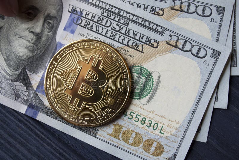 Goldenes bitcoin und Dollar in der männlichen Hand auf einem dunkelblauen hölzernen Hintergrund