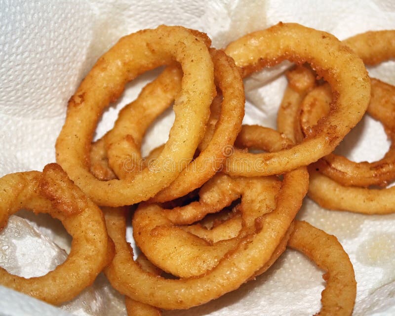 Golden brown deep fried Onion Rings set on paper towel to absorb grease. Golden brown deep fried Onion Rings set on paper towel to absorb grease