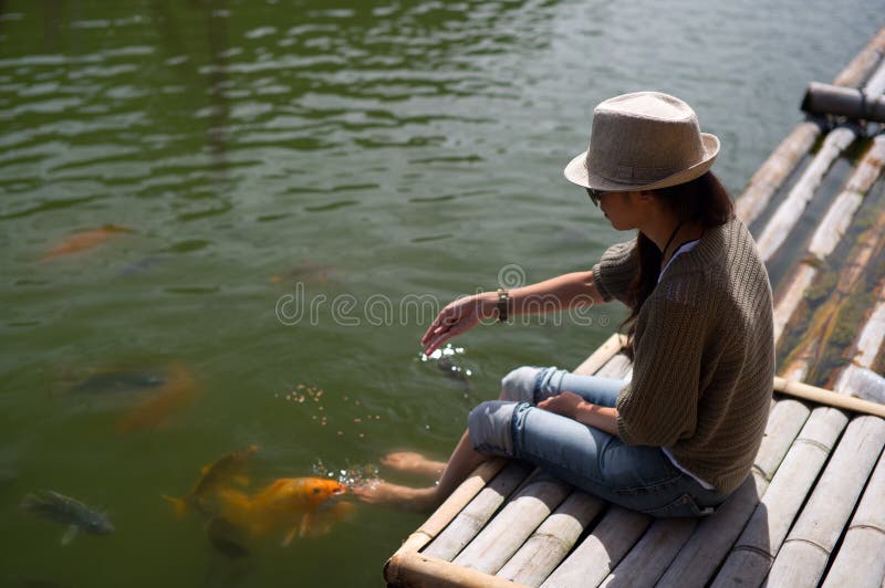 Goldfish que introduce de la mujer del muelle de bambú fotografía de archivo Goldfish que introduce de la mujer del muelle de bambú fotografía de archivo