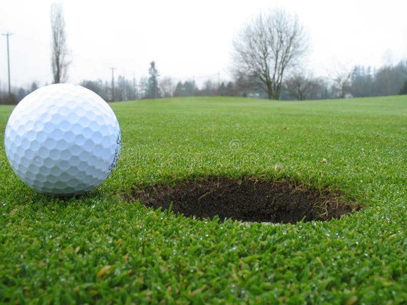 Golf ball beside hole