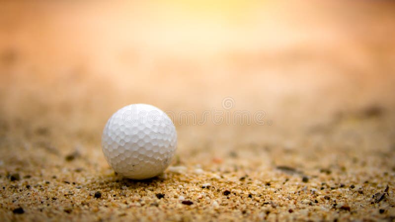 Golf ball on sand in golf course on sunset