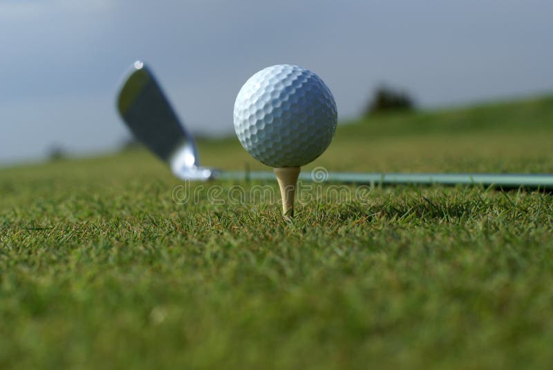 Golf ball in tall green grass against blue sky