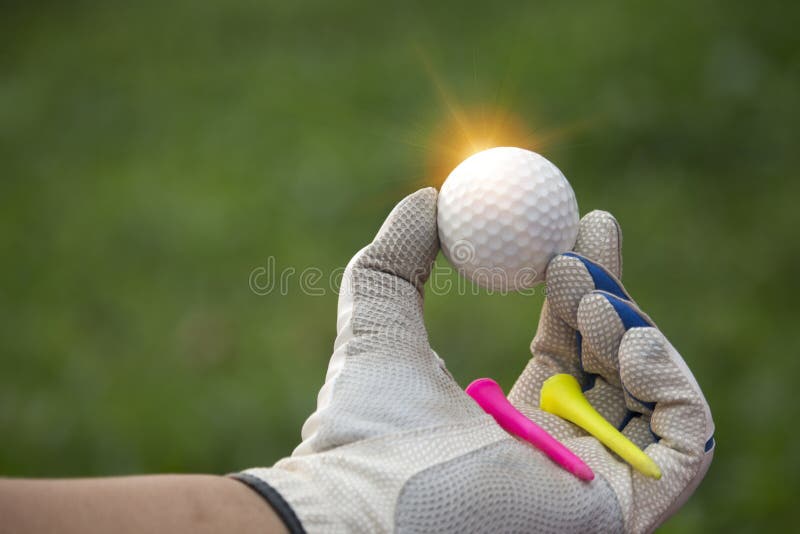 Golf balls and tee in the hands that are worn with white gloves