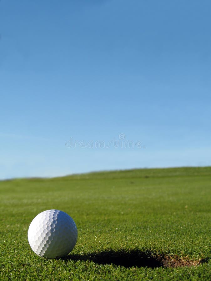 Golf course ball beside hole