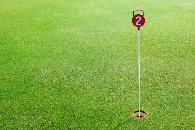 Golf el agujero del putting green de la práctica y marcado con una muestra roja fotografía de archivo libre de regalías Golf el agujero del putting green de la práctica y marcado con una muestra roja fotografía de archivo libre de regalías