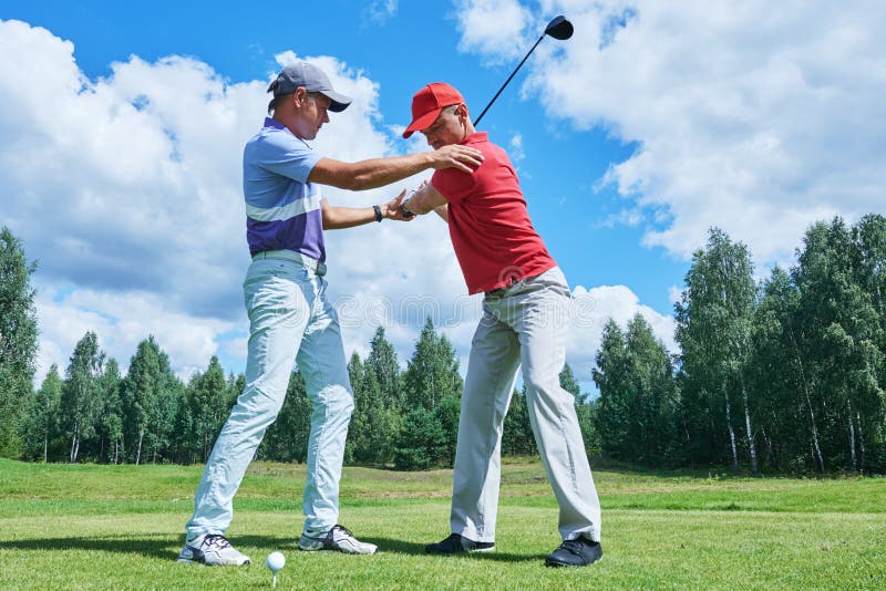 Golf training. Instructor trains new player in summer