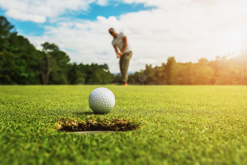 golf player putting golf ball into hole