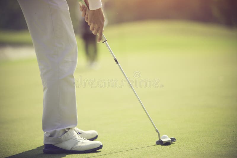 Golf Player at the Putting Green Hitting Ball into a Hole Stock Photo