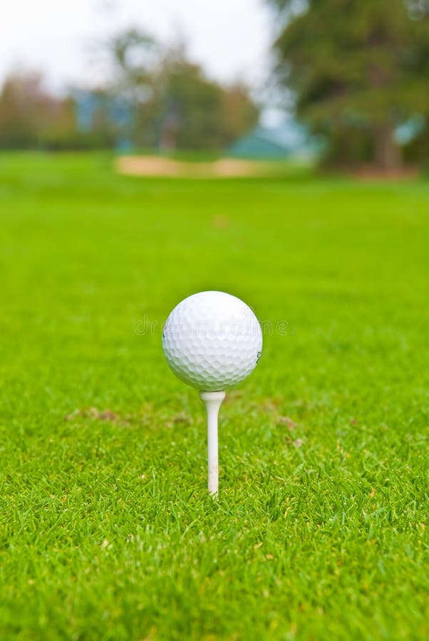 Golf ball on tee over a blurred green. Shallow depth of field. Focus on the ball. Golf ball on tee over a blurred green. Shallow depth of field. Focus on the ball.