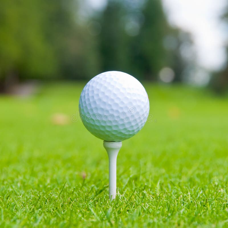 Golf ball on tee over a blurred green. Shallow depth of field. Focus on the ball. Golf ball on tee over a blurred green. Shallow depth of field. Focus on the ball.