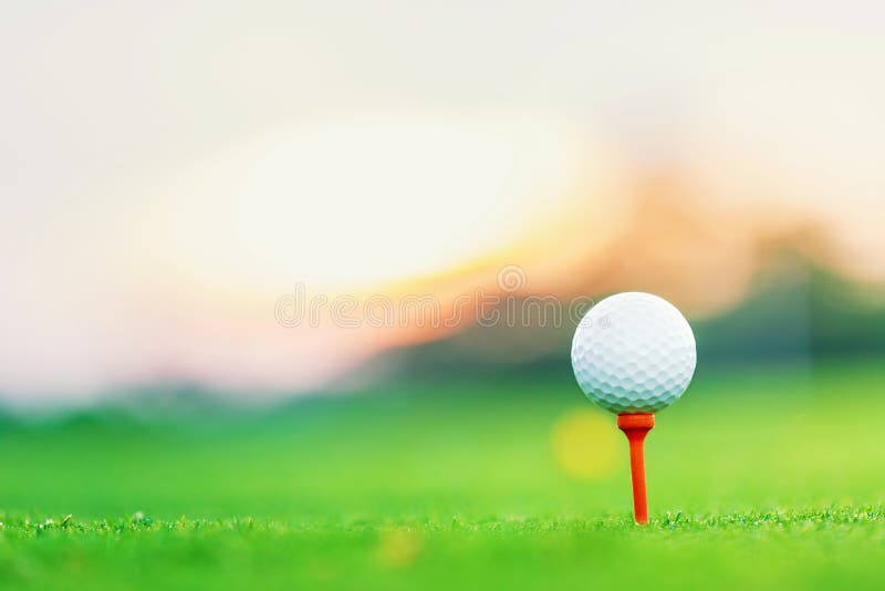 Golfbal op T-stuk bij T-stuk weg met voorgrond van het onduidelijk beeld de groene gras en onduidelijk beeld kleurrijke hemel met stock foto Golfbal op T-stuk bij T-stuk weg met voorgrond van het onduidelijk beeld de groene gras en onduidelijk beeld kleurrijke hemel met stock foto