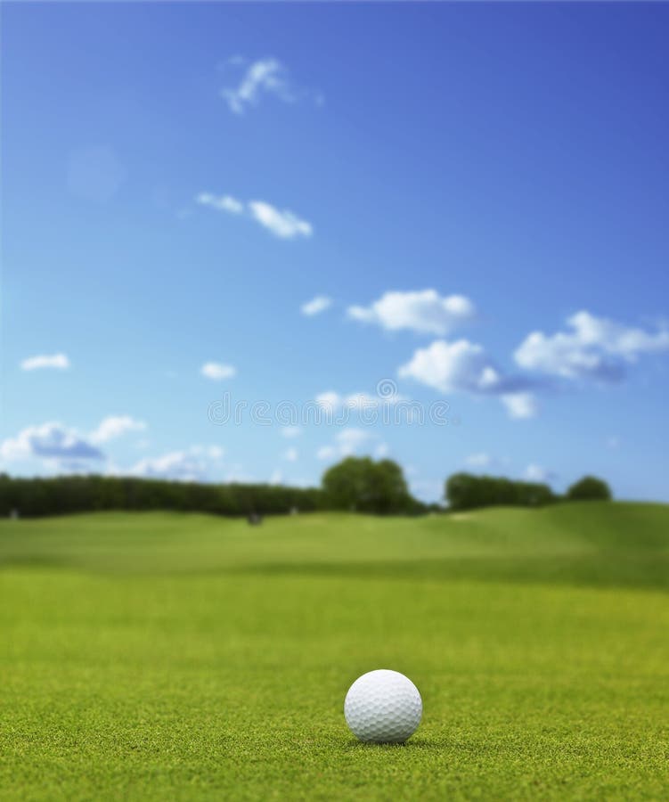 Bílé golfball, kterým se na golfovém hřišti pod modrým nebem.