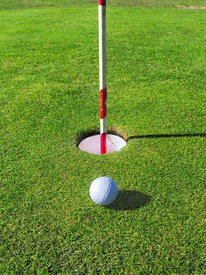 A golf ball lands near the hole on the green. A golf ball lands near the hole on the green.
