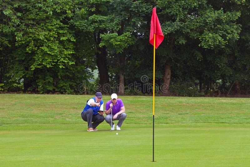 Golfer and caddy reading the line of putt