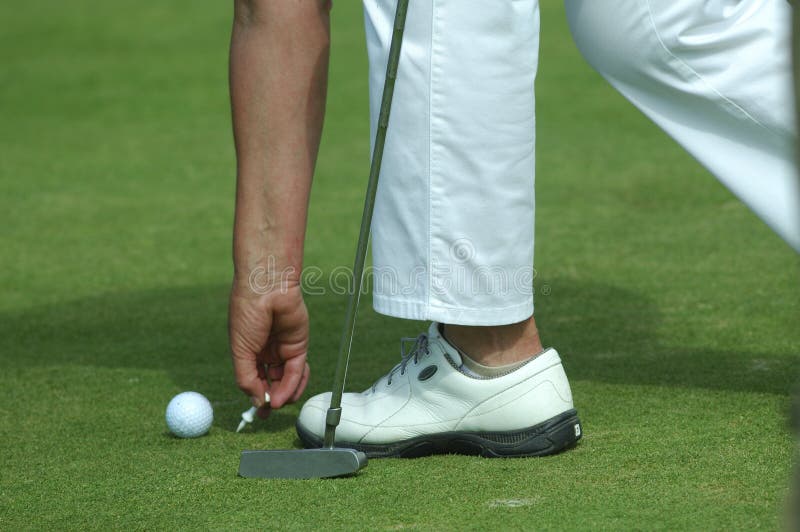 Golfer Placing Golf Ball on Tee on a Sunny Day at Course Stock Photo
