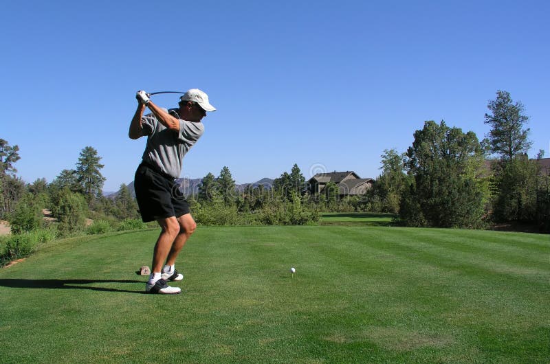 Golfista asi řídit golfový míček z odpaliště box s hlubokou modrou oblohu.