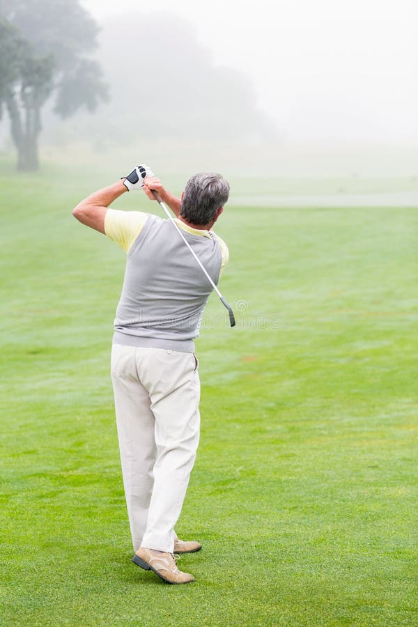 Golfista que balancea a su club en el curso fotografía de archivo libre de regalías Golfista que balancea a su club en el curso fotografía de archivo libre de regalías