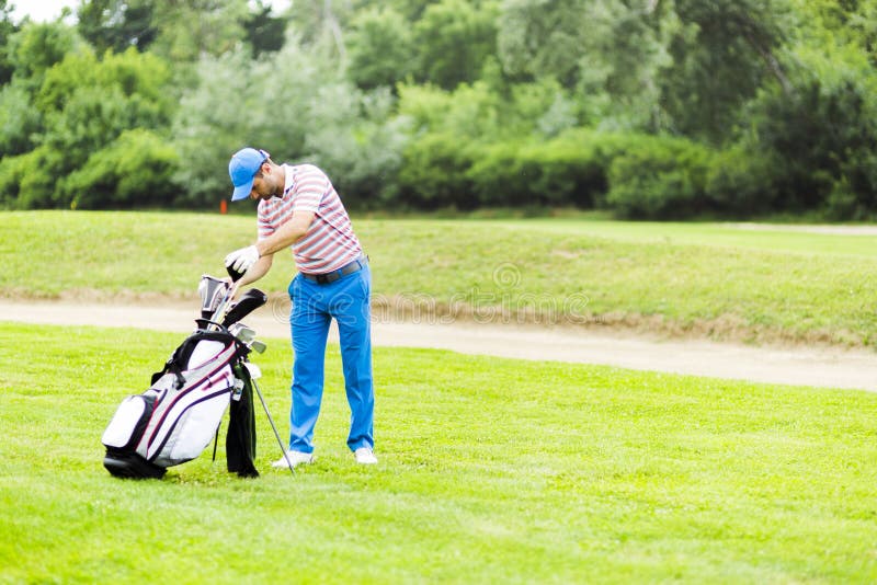 Golfista que selecciona al club apropiado imagen de archivo libre de regalías Golfista que selecciona al club apropiado imagen de archivo libre de regalías