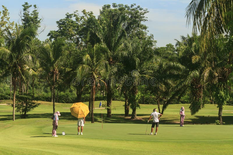 Golfistas y caddies en campo de golf en Tailandia imagen de archivo Golfistas y caddies en campo de golf en Tailandia imagen de archivo