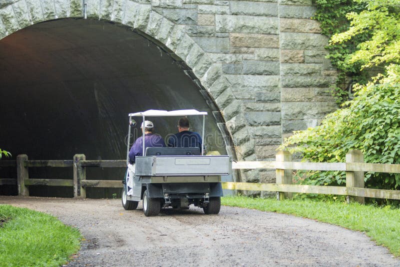 Golfkar op vuilweg die onder een brug gaan royalty-vrije stock afbeeldingen Golfkar op vuilweg die onder een brug gaan royalty-vrije stock afbeeldingen