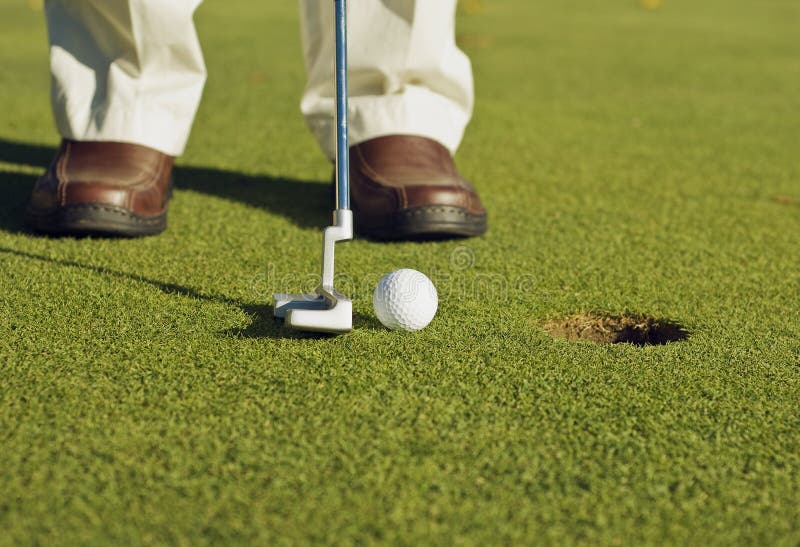 A golfer is making a very easy putt. A golfer is making a very easy putt.