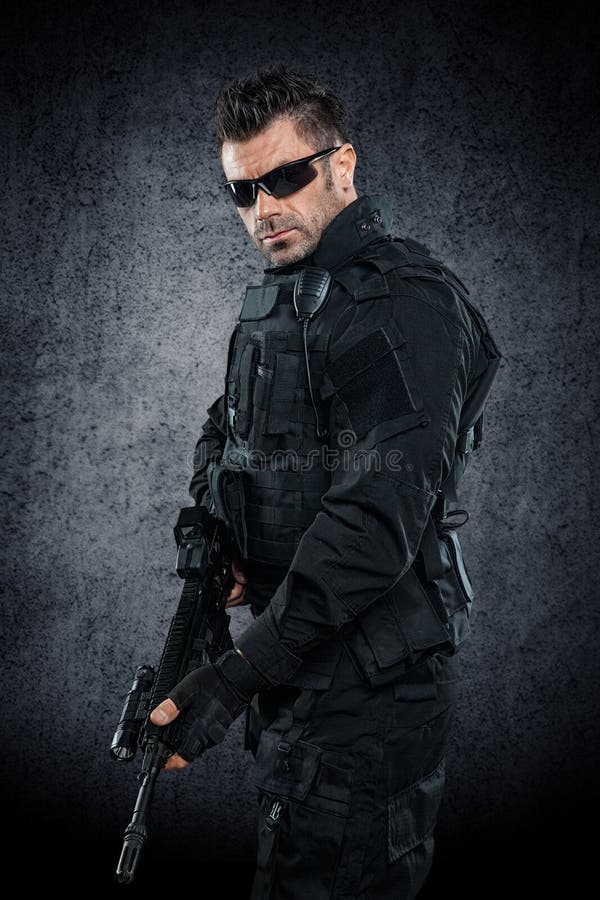 GOLPE do agente da polícia dos ops das especs. no estúdio uniforme preto fotografia de stock GOLPE do agente da polícia dos ops das especs. no estúdio uniforme preto fotografia de stock