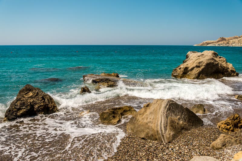 Golven die Pissouri-kiezelsteenstrand ingaan door grote rotsen in het water, Cyprus royalty-vrije stock afbeelding Golven die Pissouri-kiezelsteenstrand ingaan door grote rotsen in het water, Cyprus royalty-vrije stock afbeelding