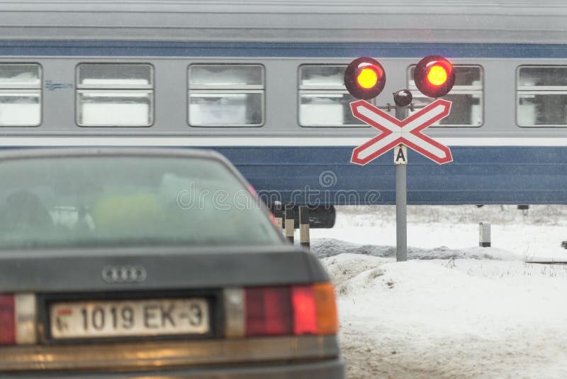 Gomel, Weißrussland - 25. Dezember 2016: Autos sind am Bahnübergang, und am geführten Zug lizenzfreies stockbild Gomel, Weißrussland - 25. Dezember 2016: Autos sind am Bahnübergang, und am geführten Zug lizenzfreies stockbild