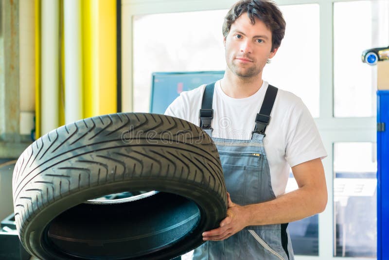 Meccanico che cambia una gomma in officina immagine stock